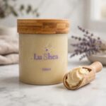Lu Shea organic shea butter jar with a wooden scoop of whipped butter